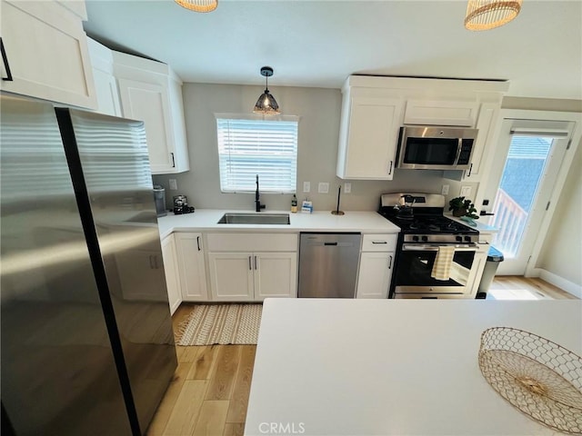 kitchen featuring a sink, white cabinetry, light countertops, appliances with stainless steel finishes, and light wood finished floors