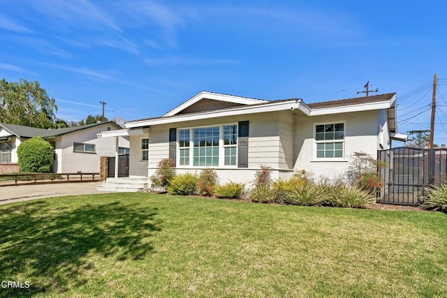 view of front of house with stucco siding, a gate, fence, and a front yard