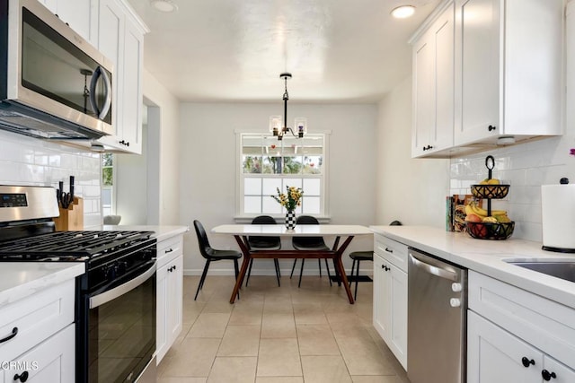 kitchen featuring stainless steel appliances, backsplash, white cabinets, light tile patterned flooring, and baseboards