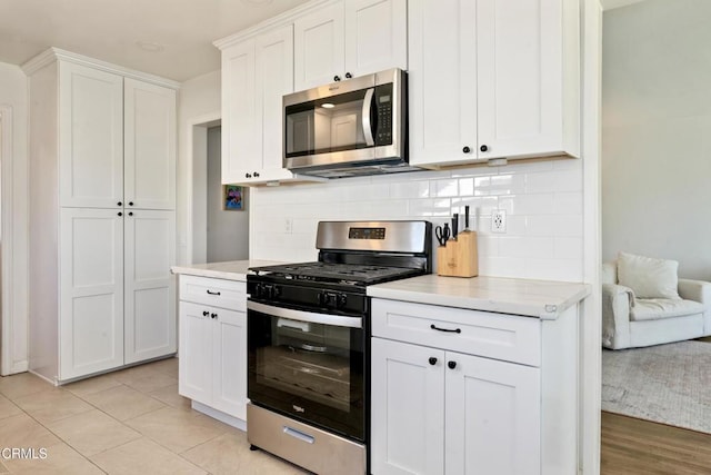 kitchen featuring white cabinets, tasteful backsplash, stainless steel appliances, and light tile patterned flooring