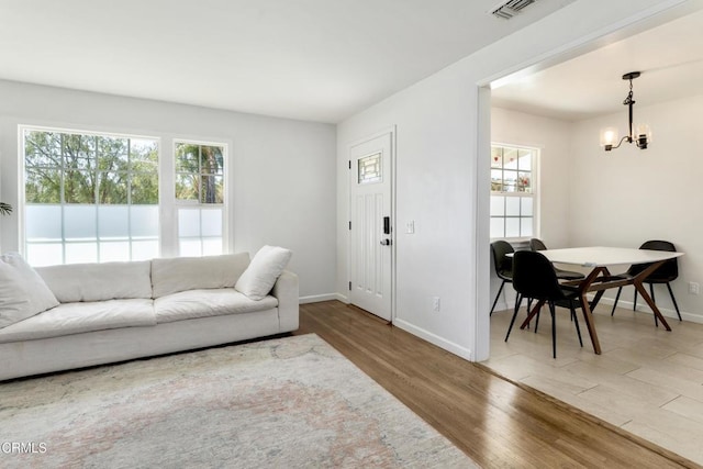 living room featuring a chandelier, a wealth of natural light, baseboards, and wood finished floors