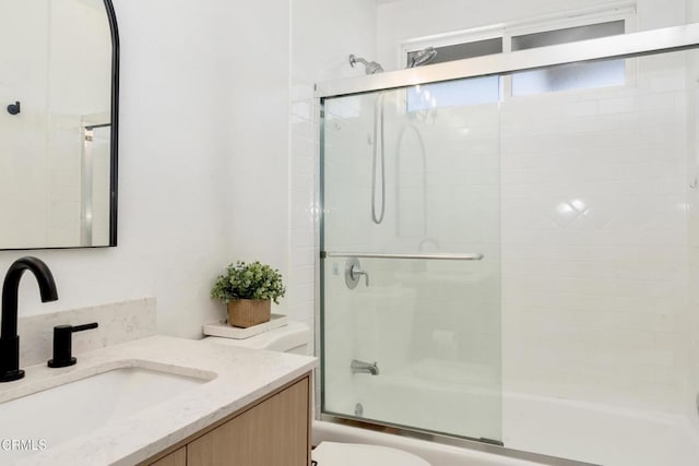 full bathroom featuring toilet, shower / bath combination with glass door, and vanity