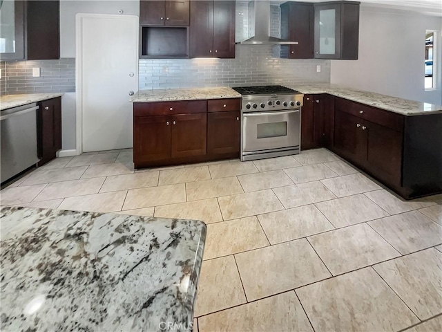 kitchen featuring dark brown cabinetry, wall chimney range hood, light stone counters, and stainless steel appliances