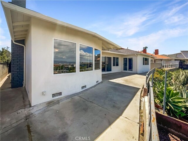 rear view of property featuring crawl space, a patio area, and stucco siding