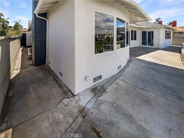 view of side of home featuring crawl space, a patio, fence, and stucco siding