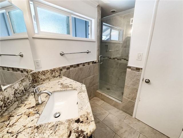 bathroom with tile patterned flooring, a shower stall, vanity, and tile walls