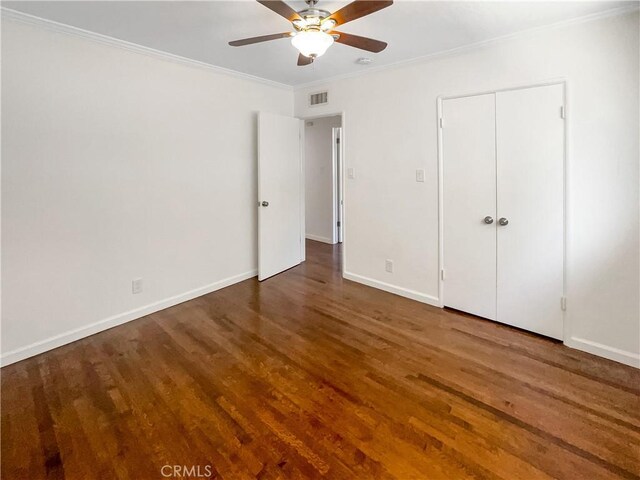 unfurnished bedroom with wood finished floors, a ceiling fan, visible vents, baseboards, and ornamental molding