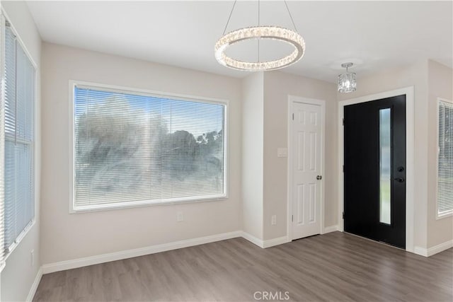 foyer with a notable chandelier, wood finished floors, and baseboards