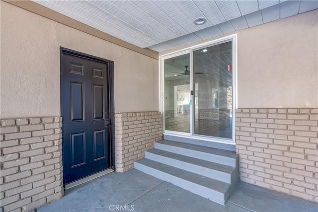 doorway to property featuring stucco siding and brick siding