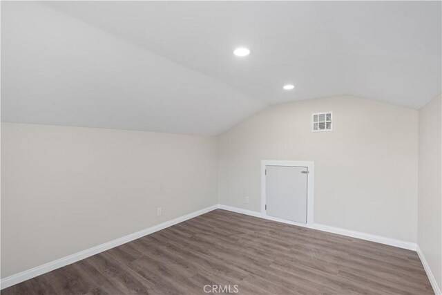 additional living space with lofted ceiling, wood finished floors, visible vents, and baseboards