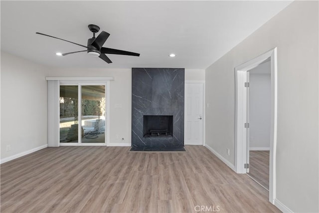 unfurnished living room featuring recessed lighting, a ceiling fan, a high end fireplace, baseboards, and light wood finished floors