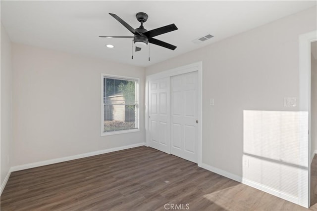 unfurnished bedroom with a closet, visible vents, ceiling fan, wood finished floors, and baseboards