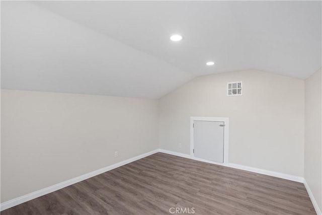 bonus room featuring visible vents, baseboards, vaulted ceiling, and wood finished floors