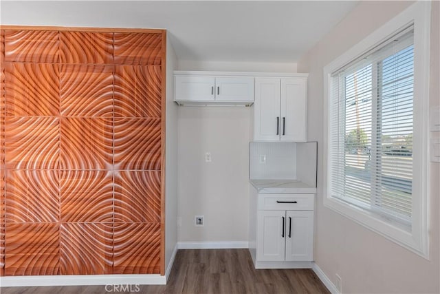 kitchen with baseboards, tasteful backsplash, wood finished floors, and white cabinets