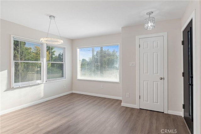 unfurnished dining area featuring wood finished floors and baseboards