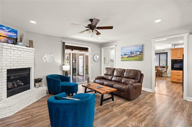 living area with recessed lighting, a fireplace, baseboards, and wood finished floors