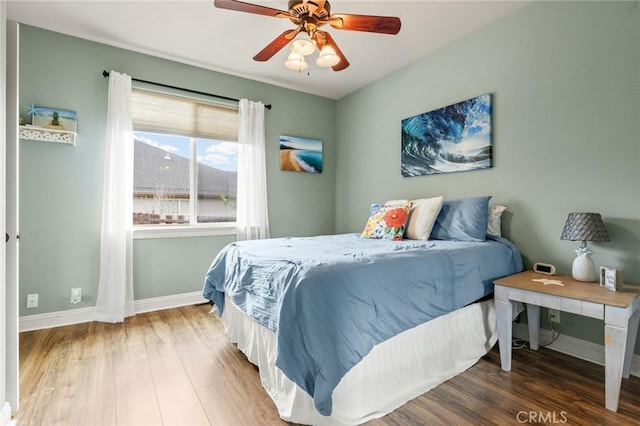 bedroom featuring a ceiling fan, baseboards, and wood finished floors