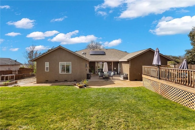 back of property featuring a patio, crawl space, a lawn, roof mounted solar panels, and stucco siding