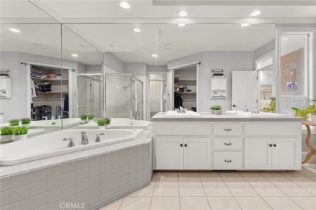 full bath with a spacious closet, a shower stall, a bath, and tile patterned floors