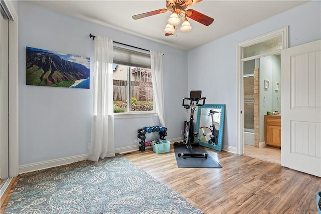 workout room with light wood finished floors, a ceiling fan, and baseboards