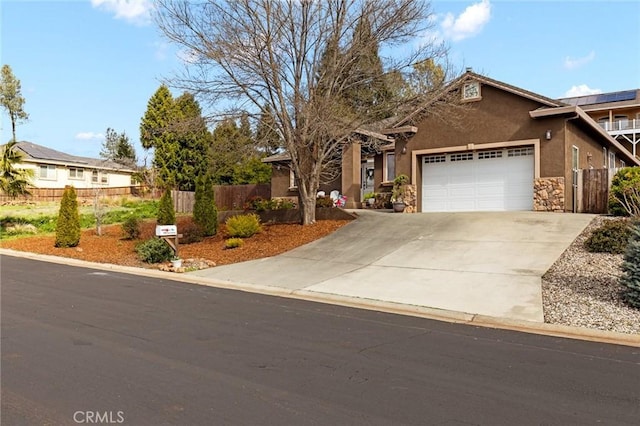 ranch-style home featuring concrete driveway, fence, an attached garage, and stucco siding