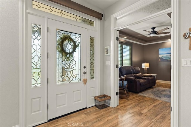 entrance foyer featuring ornamental molding, light wood-type flooring, ceiling fan, and baseboards