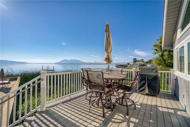 wooden terrace with outdoor dining space and a water and mountain view