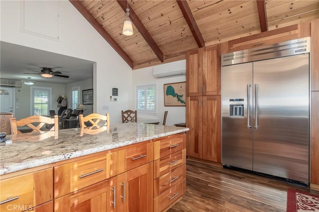 kitchen with a wall unit AC, lofted ceiling with beams, light stone countertops, stainless steel built in refrigerator, and a wealth of natural light