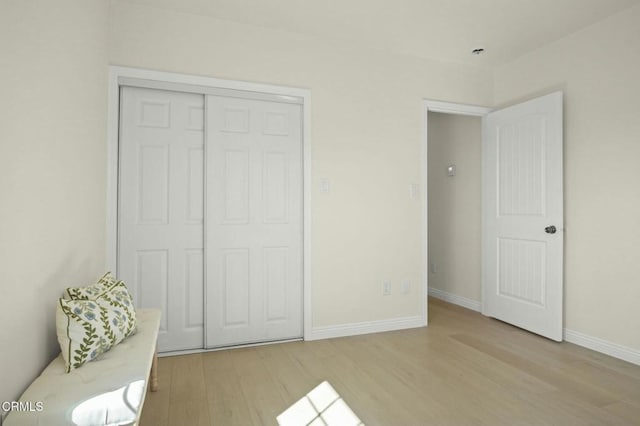 bedroom with light wood finished floors, a closet, and baseboards