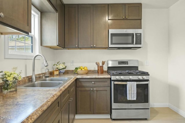 kitchen featuring light countertops, baseboards, appliances with stainless steel finishes, and a sink