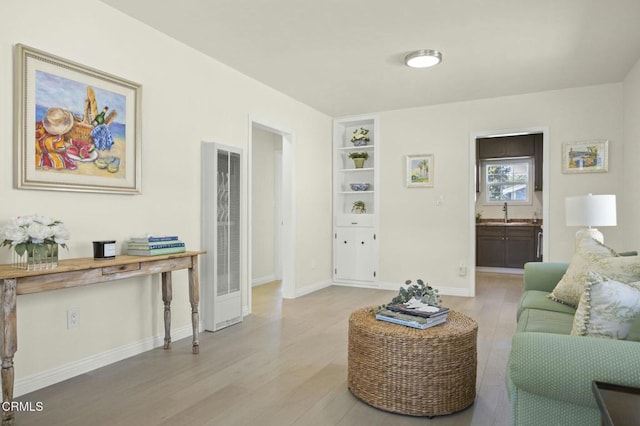 living room featuring baseboards, a heating unit, and light wood finished floors