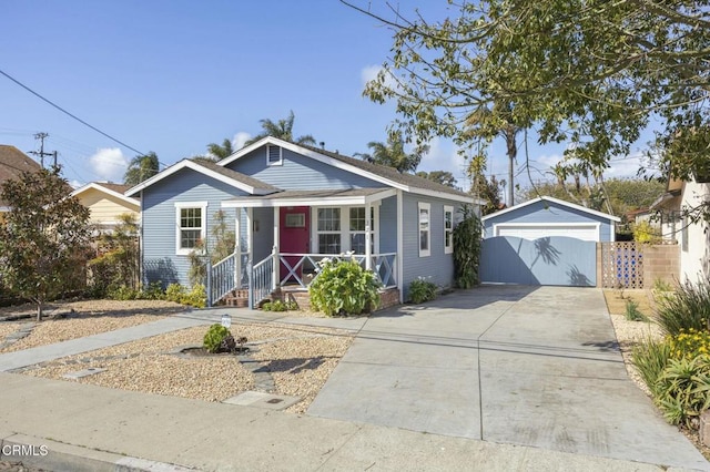 bungalow with a porch, concrete driveway, a detached garage, and an outdoor structure