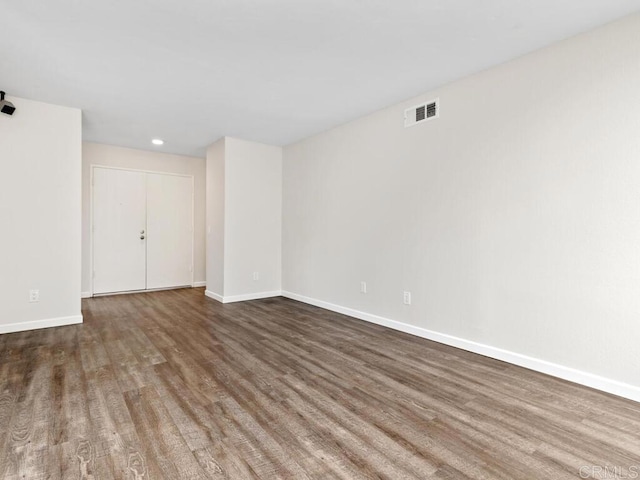 empty room with wood finished floors, visible vents, and baseboards