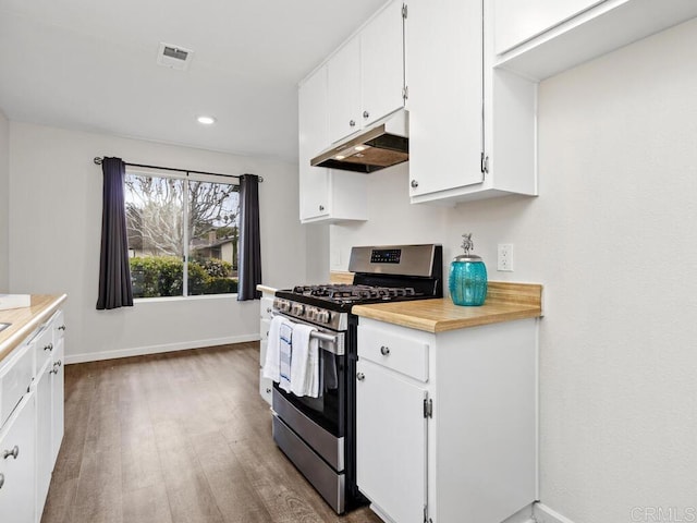 kitchen featuring visible vents, white cabinets, wood finished floors, stainless steel gas range, and under cabinet range hood