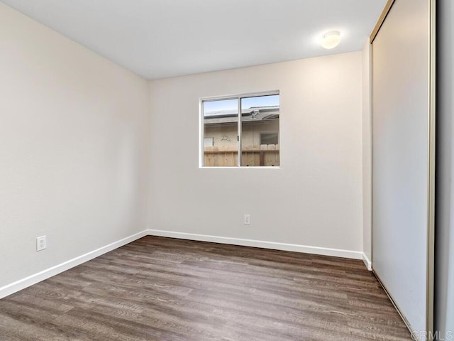 spare room featuring baseboards and wood finished floors