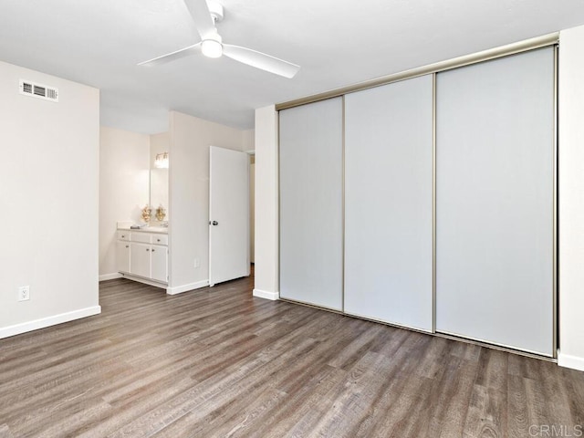 unfurnished bedroom featuring a closet, wood finished floors, visible vents, and baseboards