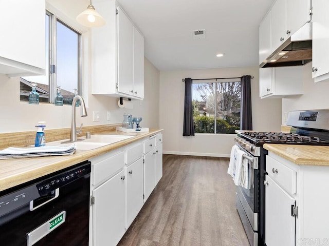 kitchen with black dishwasher, light countertops, stainless steel gas stove, a sink, and white cabinetry