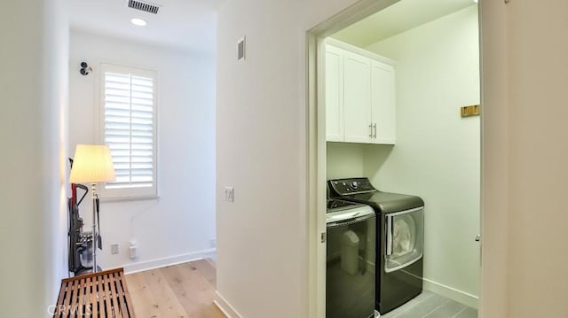 clothes washing area featuring a healthy amount of sunlight, visible vents, cabinet space, and separate washer and dryer