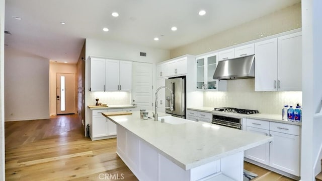 kitchen with stainless steel appliances, backsplash, white cabinets, and under cabinet range hood