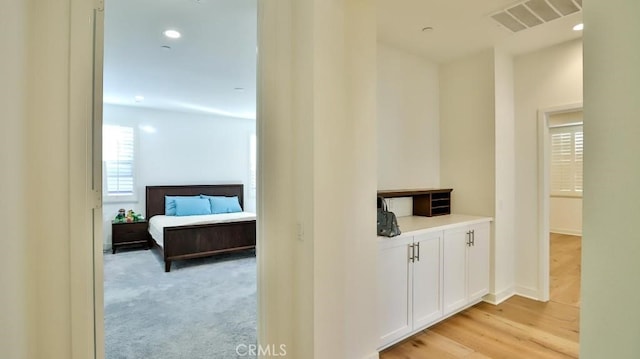 hall with light carpet, light wood-style flooring, visible vents, and recessed lighting