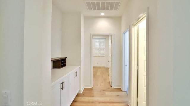 corridor with baseboards, light wood-type flooring, visible vents, and recessed lighting