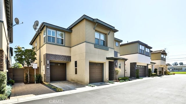 contemporary house with brick siding, an attached garage, and stucco siding