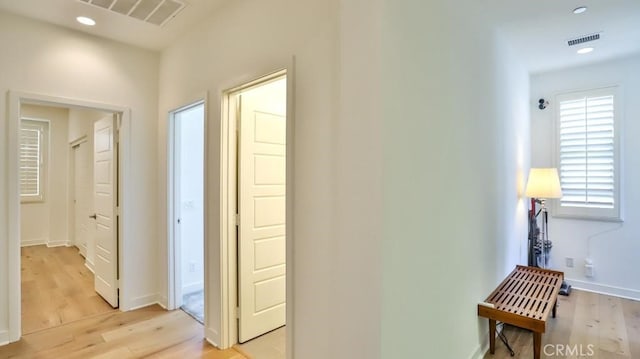 hallway featuring light wood-type flooring, baseboards, visible vents, and recessed lighting