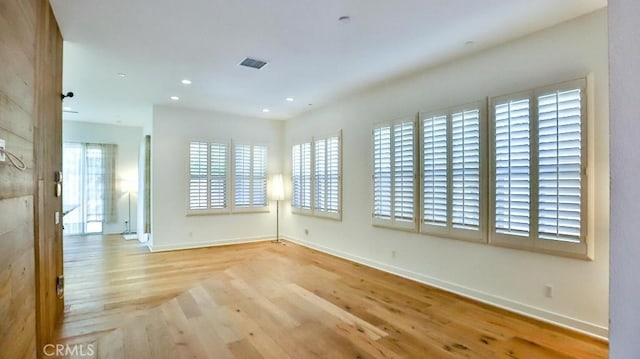 spare room featuring recessed lighting, wood finished floors, and baseboards