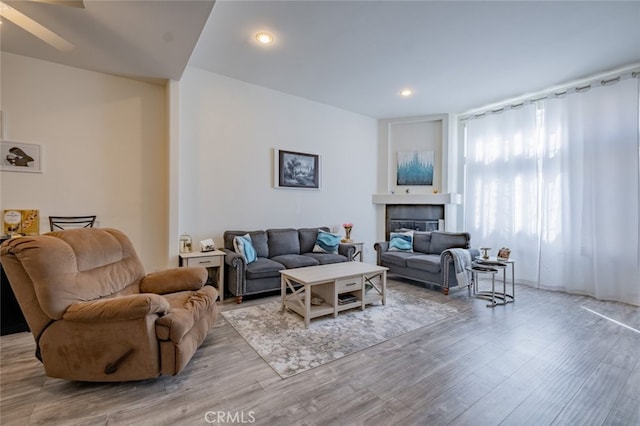 living room featuring a tiled fireplace, recessed lighting, and wood finished floors