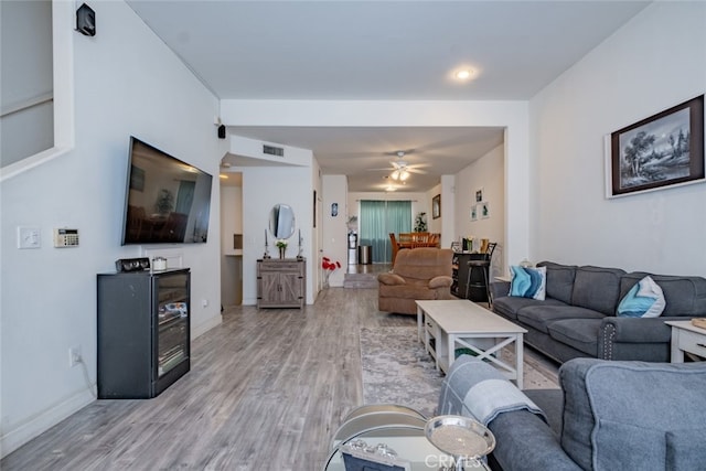 living area featuring baseboards, visible vents, light wood finished floors, and ceiling fan