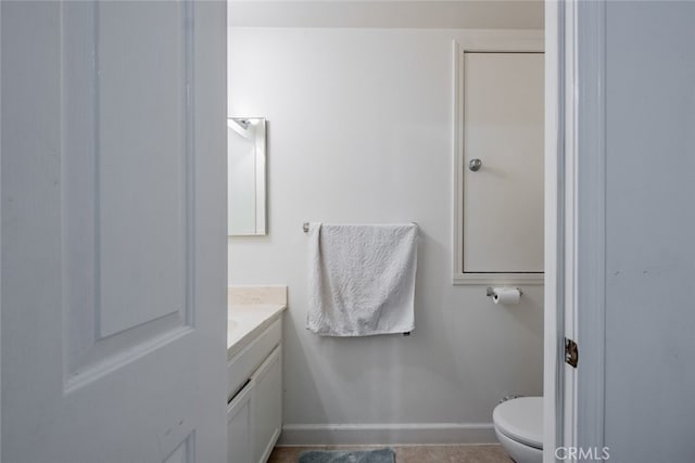 bathroom with toilet, vanity, and baseboards