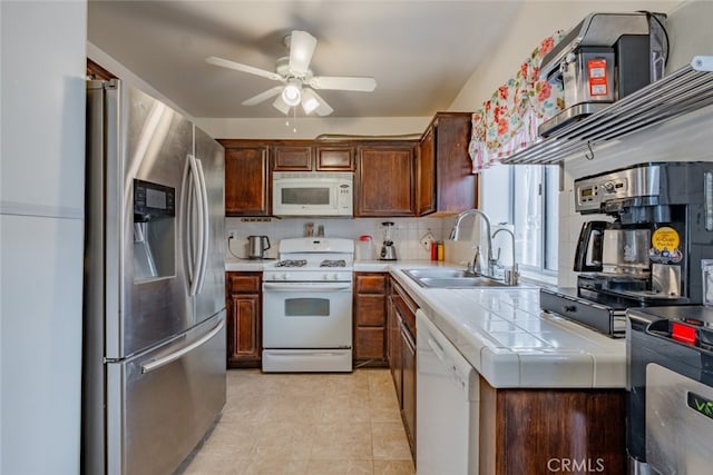 kitchen with white appliances, tile countertops, a ceiling fan, a sink, and backsplash