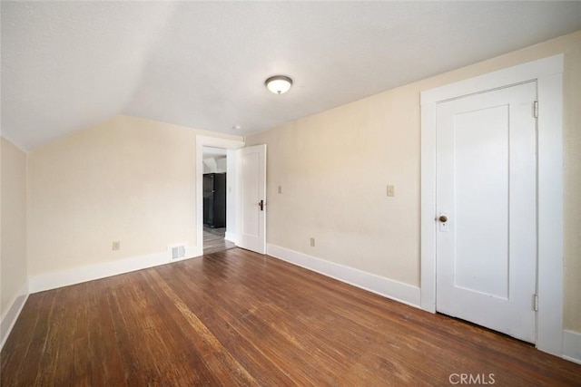 additional living space featuring vaulted ceiling, wood finished floors, visible vents, and baseboards