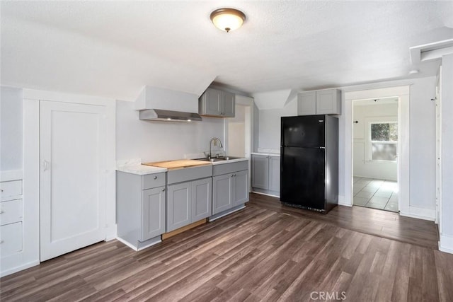 kitchen with gray cabinetry, light countertops, freestanding refrigerator, and a sink